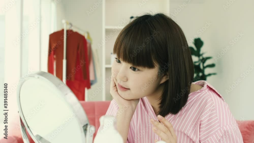 Young asian short bob hairstyle woman apply skincare lotion on her face infront of mirror portable. Young asian short bob hairstyle woman apply skincare lotion on her face infront of mirror portable.