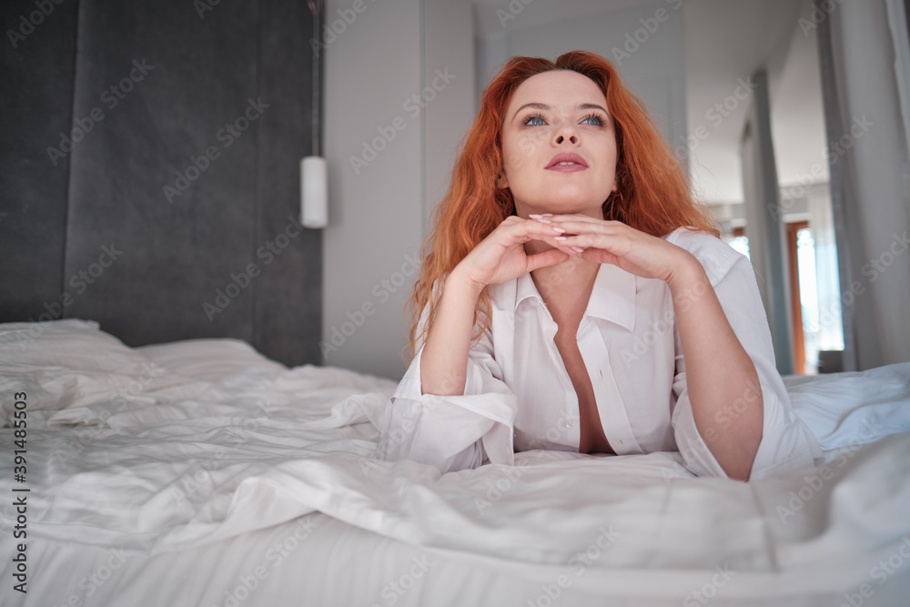 cute red hair woman in white shirt relax on the bed in her white room cute red hair woman in white shirt relax on the bed in her white room