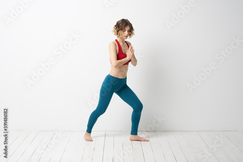 A woman in full growth In a bright room yoga meditation is engaged in sports