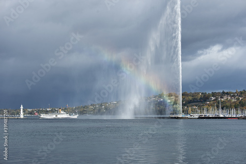 vintage steamboat arriving in the harbor with the water jet and a rainbow in Geneva, Switzerland