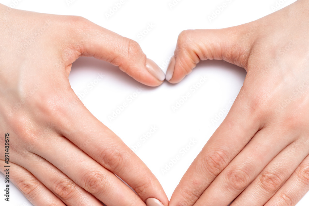 Fototapeta premium Closeup of hands of young woman forming shape of heart with her manicured fingers on white background