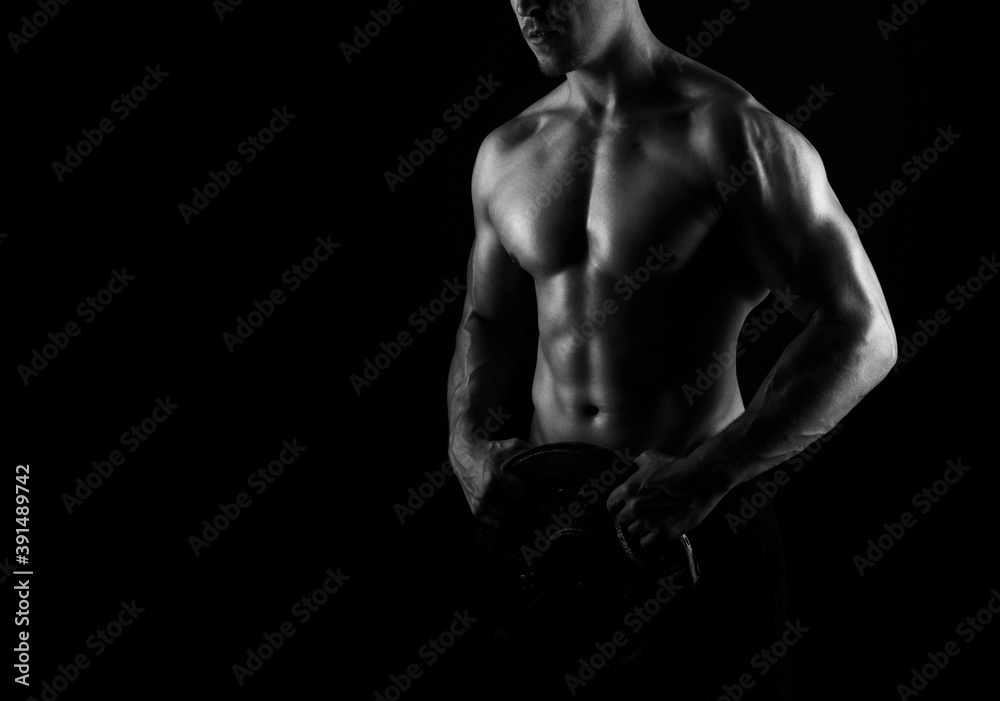 Muscular male torso of fit bodybuilder on black background in black and white Muscular male torso of fit bodybuilder on black background in black and white