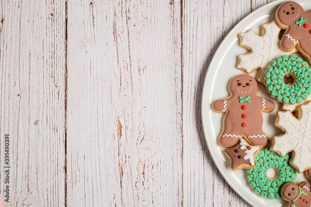 Christmas cookies and gingerbread man cookies with icing and decorations on a white weathered wooden table background with copy space and room for text. Christmas cookies and gingerbread man cookies with icing and decorations on a white weathered wooden table background with copy space and room for text.