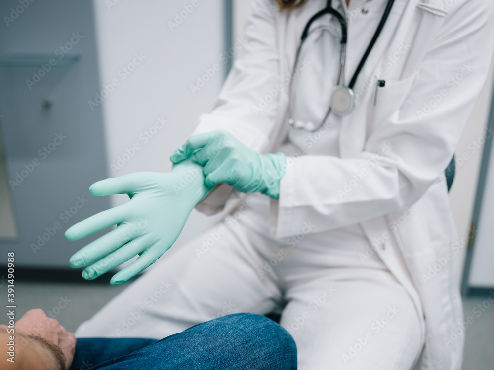 Junge Ärztin zieht sich vor der Behandlung Handschuhe an Junge Ärztin zieht sich vor der Behandlung Handschuhe an