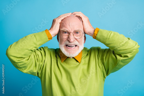 Photo of aggressive retired old man hands head mad look wear glasses green sweater isolated blue color background photo