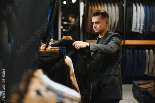 client is an elegant guy looking at the price tag of a suit jacket in a classic costume store on a hanger.