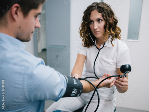 junge Ärztin misst den Blutdruck eines Patienten photo