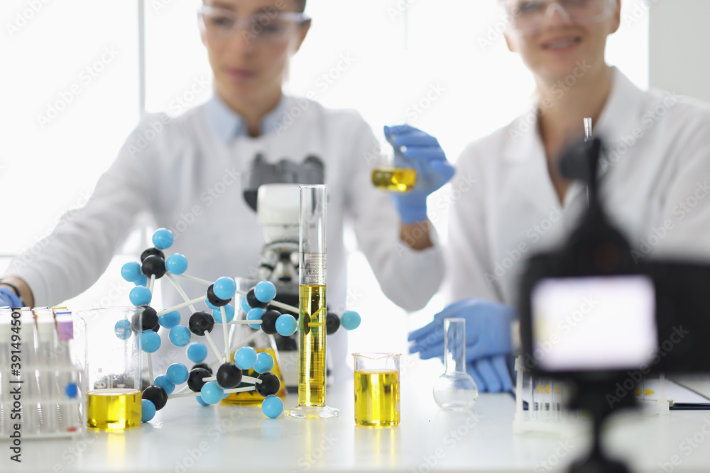 Scientists at work table on which flasks and molecules are filming experiments on video camera. Video channel about research in the field of chemistry concept Scientists at work table on which flasks and molecules are filming experiments on video camera. Video channel about research in the field of chemistry concept