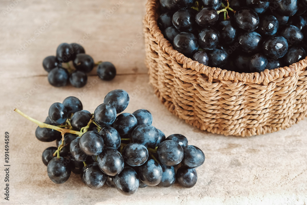 Bunch of black grapes in a round wicker basket on a old wooden table. Copy, empty space for text Bunch of black grapes in a round wicker basket on a old wooden table. Copy, empty space for text