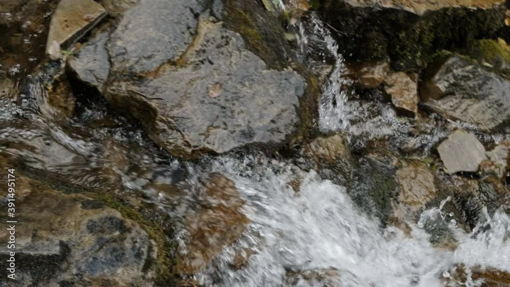 Rapid flow of mountain stream runs down, washing wet stones, close-up. Crystal clear water creek break on stones, flows between stone boulders. Fast brook originating from waterfall. 4k footage Rapid flow of mountain stream runs down, washing wet stones, close-up. Crystal clear water creek break on stones, flows between stone boulders. Fast brook originating from waterfall. 4k footage