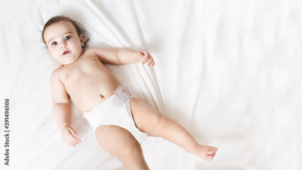 Funny little kid wearing in diaper. Portrait of a cute baby 6 months old lying on a white blanket. Beautiful toddler. Child after bath or shower on a fresh towel.Looking at the camera Funny little kid wearing in diaper. Portrait of a cute baby 6 months old lying on a white blanket. Beautiful toddler. Child after bath or shower on a fresh towel.Looking at the camera