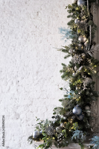 Christmas decoration of branches and garlands on the background of an old brick wall