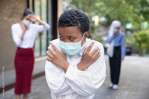 Worried and scared black African woman wearing face mask with fear in new normal lifestyle of social distancing, keeping distance away from other people in public due to pandemic