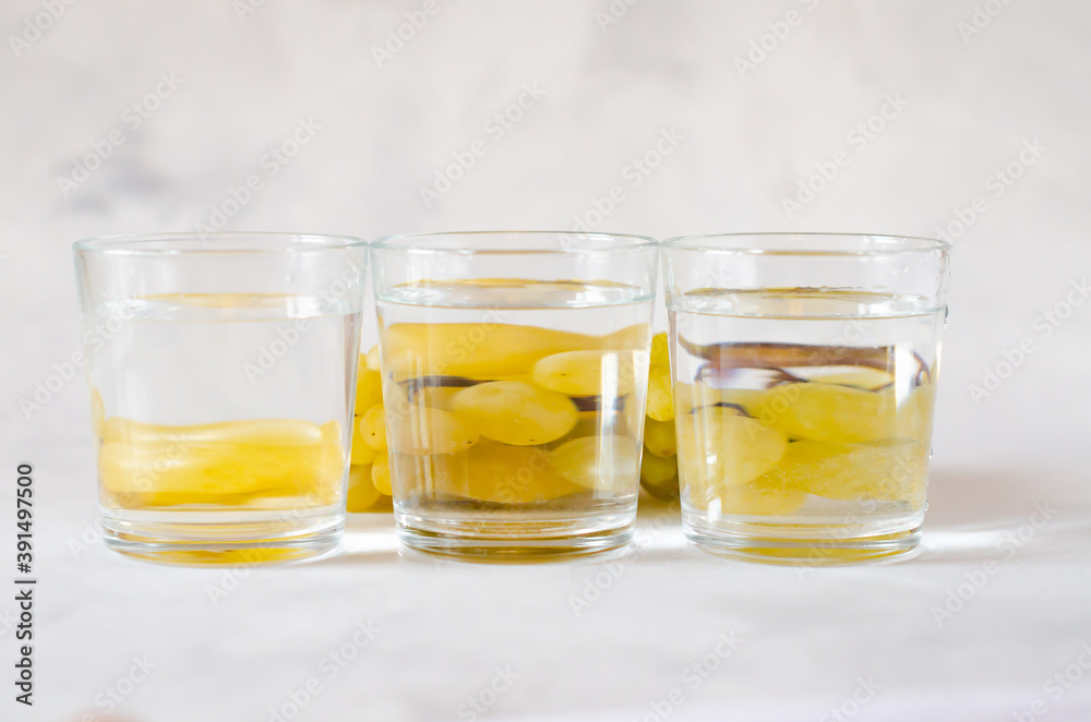 Grapes reflecting through a glass cup with water on a gray background. Distorted water image. Art concept. Minimalism. Copy space. Abstraction. Perspective, fractured and skewed images of ordinary Grapes reflecting through a glass cup with water on a gray background. Distorted water image. Art concept. Minimalism. Copy space. Abstraction. Perspective, fractured and skewed images of ordinary