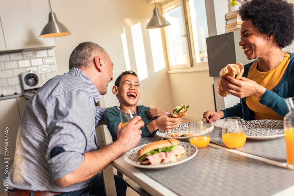 Smiling mixed race family sitting at the kitchen table having breakfast at home. Smiling mixed race family sitting at the kitchen table having breakfast at home.