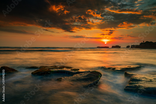 Calm ocean long exposure. Stones in mysterious mist of the sea waves. Concept of nature background. Sunset scenery background. Sun on horizon. Mengening beach  Bali  Indonesia.