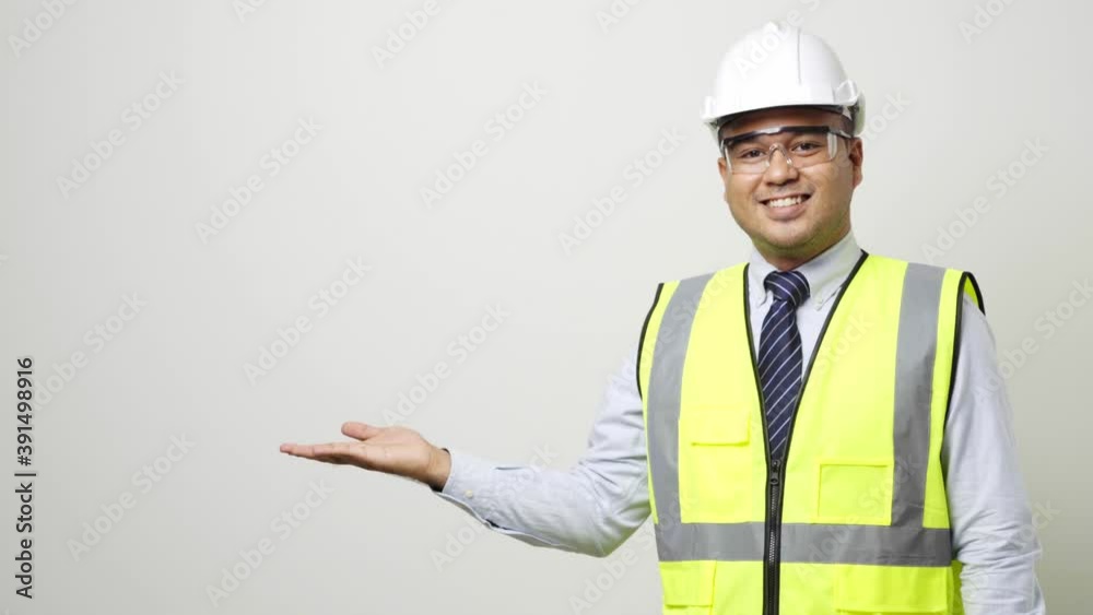 Asian worker in uniform hard hat safety glasses open hands palm up pointing to blank space for advertise text or mockup in studio isolated white background. 4k resolution. Asian worker in uniform hard hat safety glasses open hands palm up pointing to blank space for advertise text or mockup in studio isolated white background. 4k resolution.