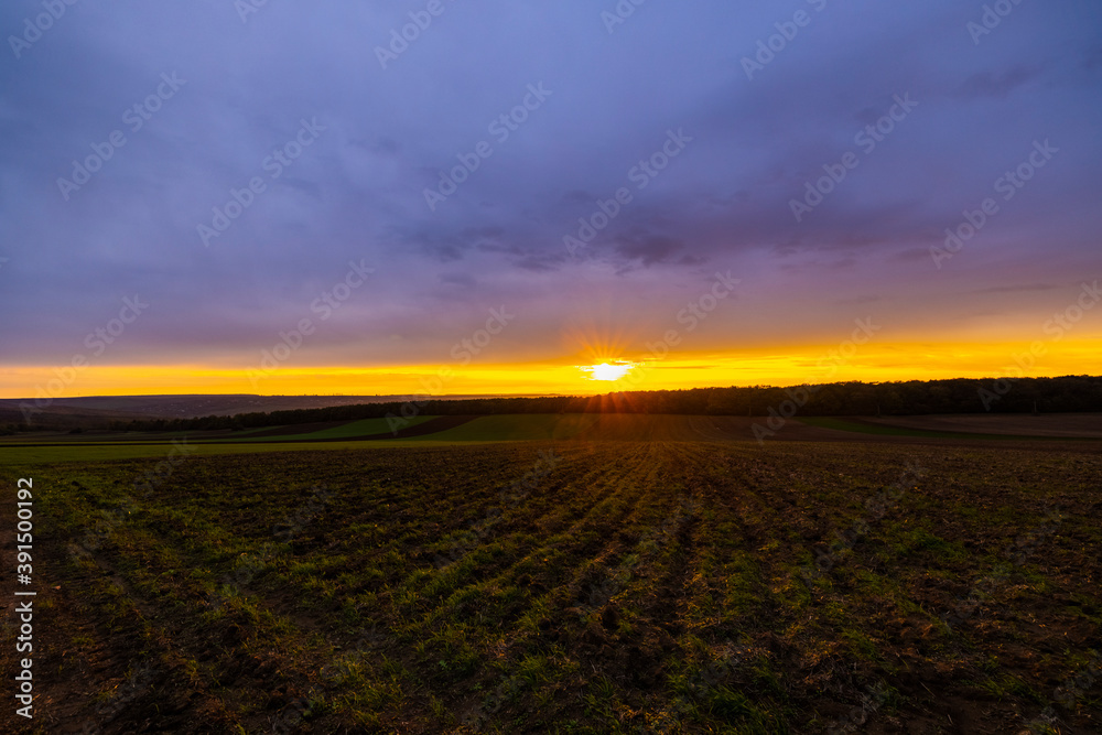 landscape with a sunset over an agricultural field in the autumn