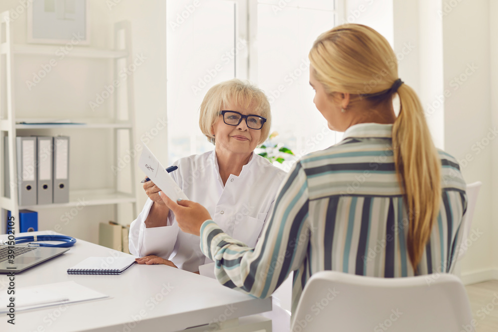 Senior female doctor prescribes medication and gives a prescription to the patient. Senior female doctor prescribes medication and gives a prescription to the patient.
