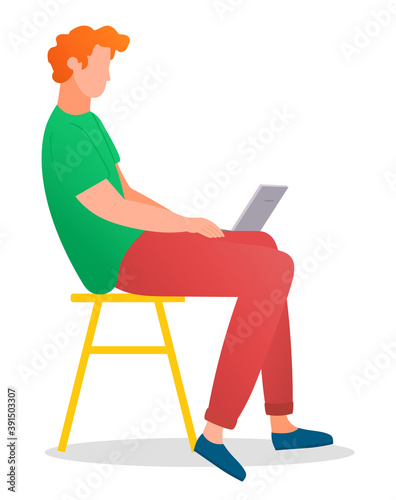 Man sitting on the tabouret and working with laptop in social networks isolated on white. Redheaded male character on the chair in casual clothes holding computer on his knees typing on the keyboard