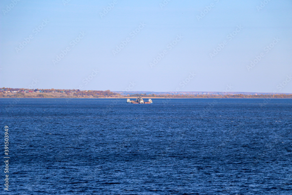 industrial merchant seagoing vessel sails on small waves in  pre-storm weather.  ship with  cargo goes to  point of delivery of  goods.