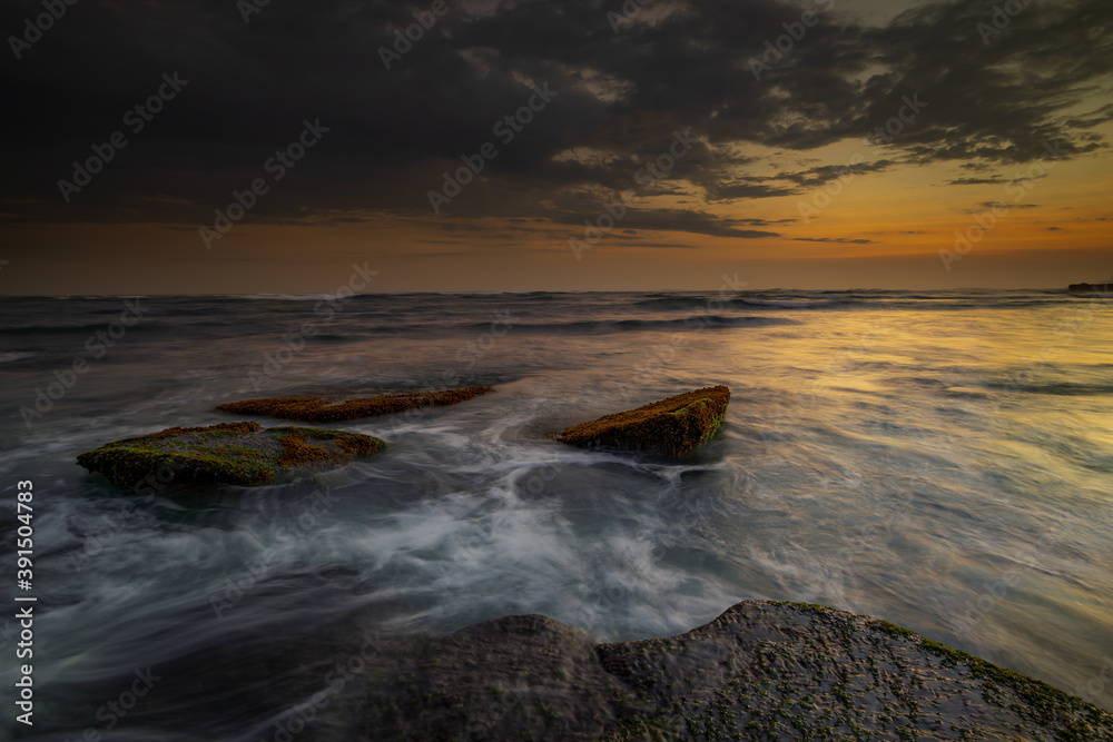 Amazing seascape with motion waves. Waterscape background. Moving water. Nature concept. Sunset scenery background. Long exposure. Mengening beach, Bali, Indonesia.