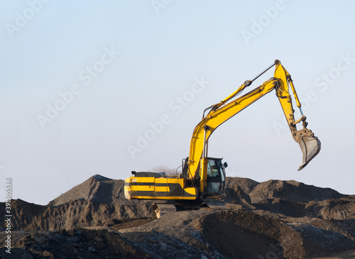 Excavator working on earthmoving at open pit mining. Backhoe digs gravel in quarry. Construction equipment and machinery for quarrying. Recycling of gravel and concrete construction waste