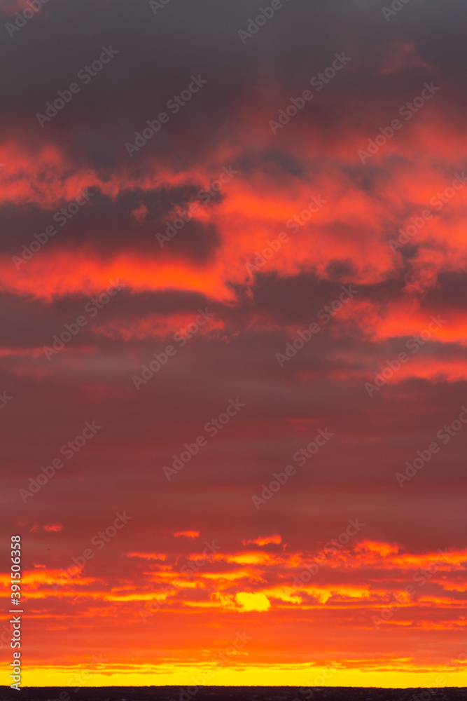 Wonderful November sunset with bright red-pink clouds on a dark gray-blue sky