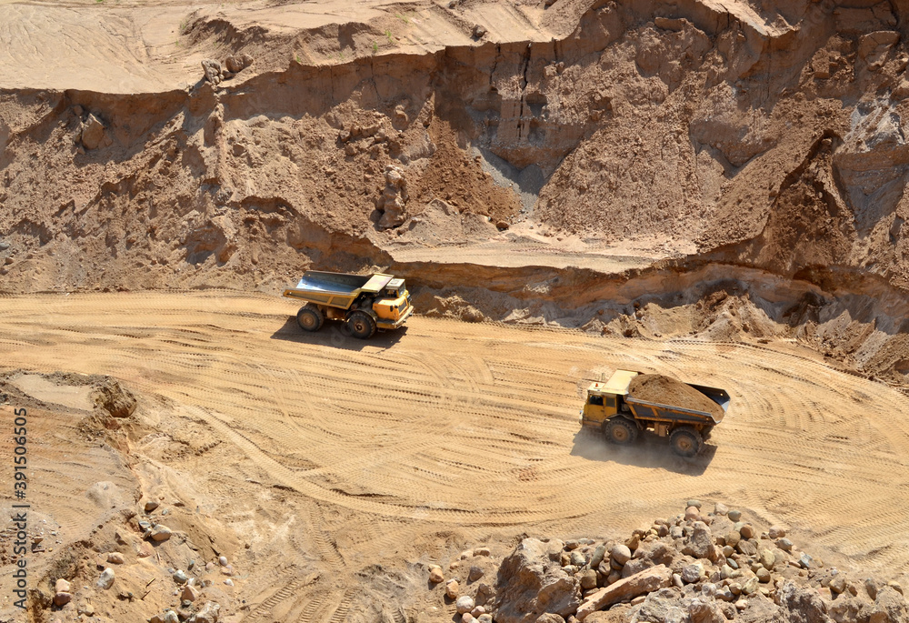 Mining trucks transports sand in an open pit. View of the quarry where