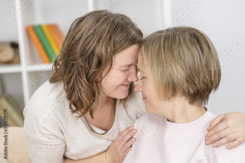 Homosexual couple of girls at home hugging and putting their heads on top of each other