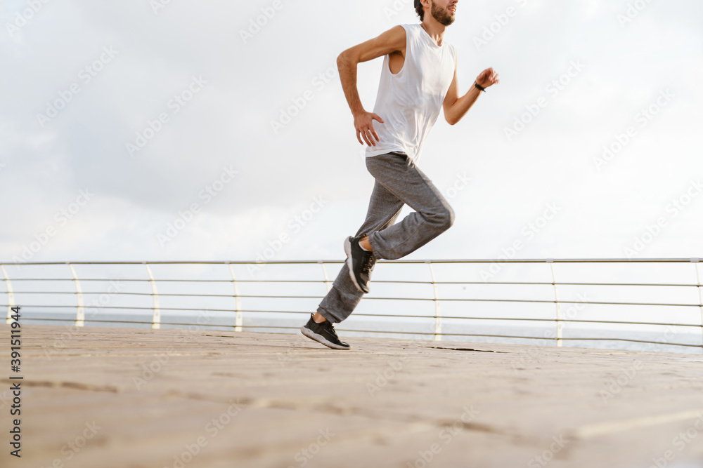 Focused unshaven guy running while working out Focused unshaven guy running while working out