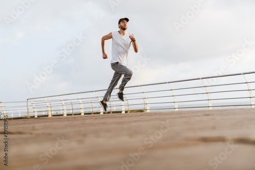 Focused unshaven guy running while working out