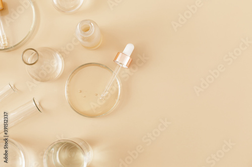 Laboratory glassware and pipette with serum and oil on beige background. Natural medicine, cosmetic research, bio science, organic skin care products. Concept skincare. Dermatology.Flat lay, top view.