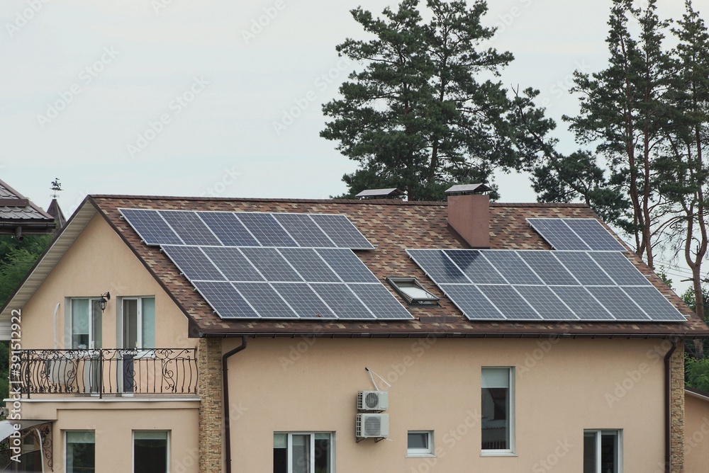 one large brown private house with tiled roof windows and gray solar panels against the sky and pine trees one large brown private house with tiled roof windows and gray solar panels against the sky and pine trees