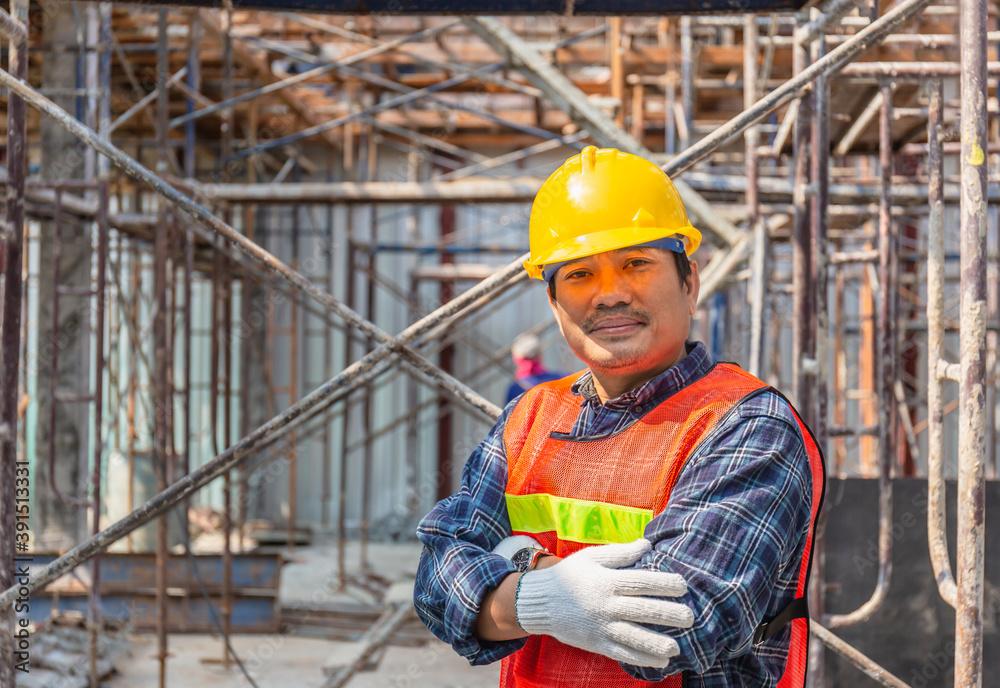 Worker checking and planning project at construction site, Smiling man with arms crossed over blurred background Worker checking and planning project at construction site, Smiling man with arms crossed over blurred background