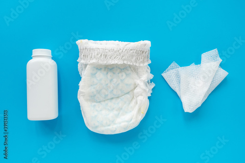 White powder, diaper, cream, napkin on a blue background, flatley, top view, copy space, mock up. Baby hygiene, background for newborn boys