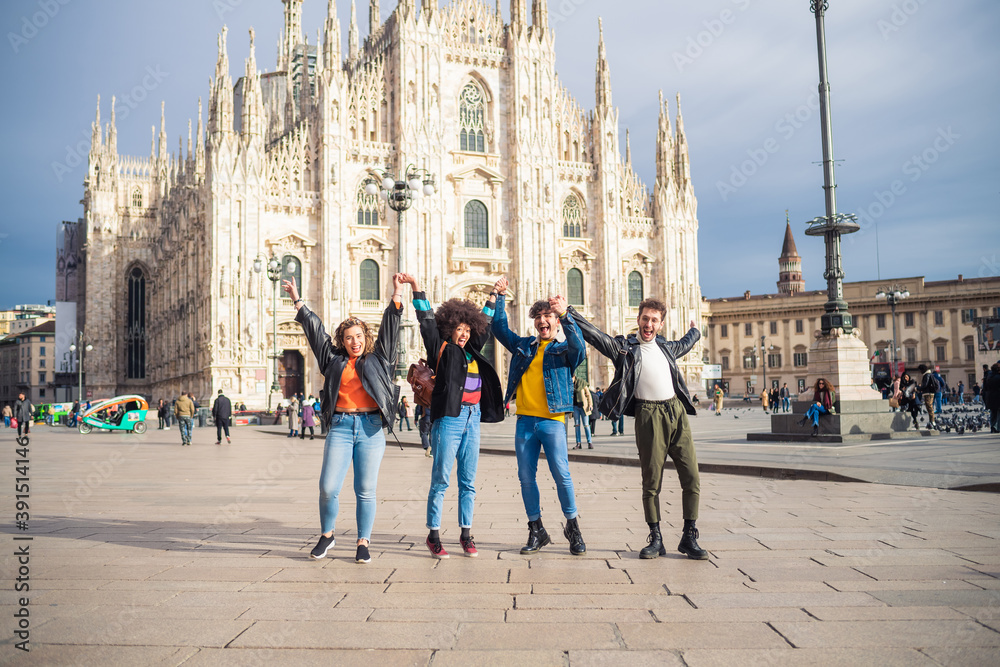 Obraz premium Group of for multiethnic people friends celebrating in front of milan cathedral rising their arms victorious thrilled after big win