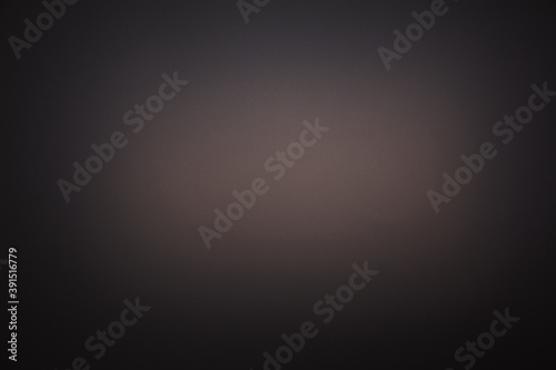 Light brown spot of light on dark gray background