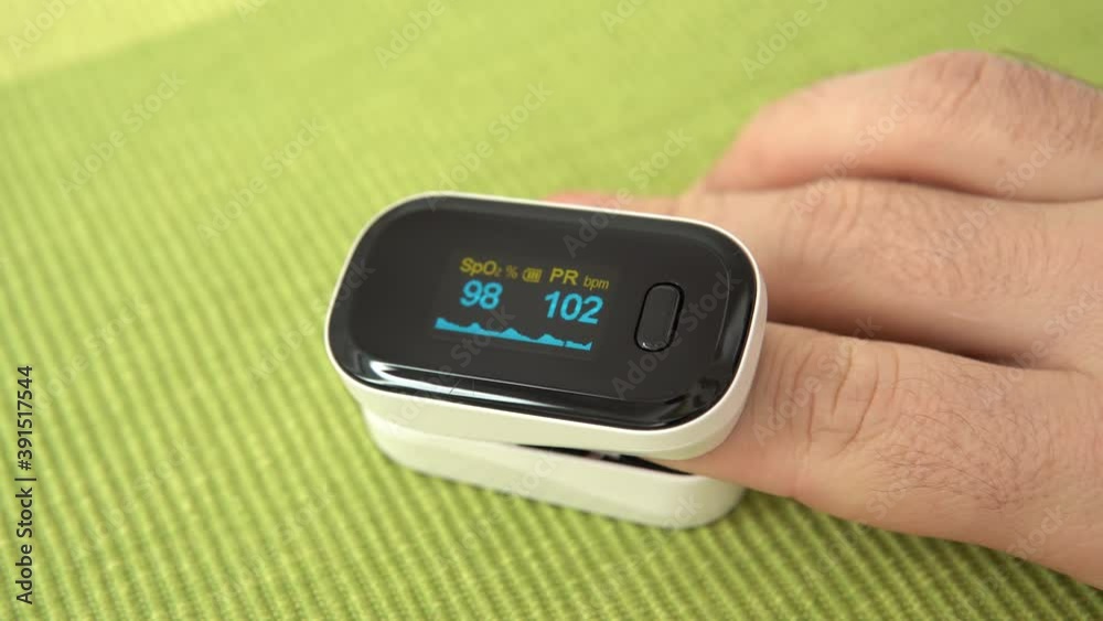 Pulse oximeter measure pulse rate, oxygen saturation level on male finger, close-up. Device shows normal level of blood oxygen, but high pulse index. Health care concept, COVID-19 pandemic. Shot in 4k Pulse oximeter measure pulse rate, oxygen saturation level on male finger, close-up. Device shows normal level of blood oxygen, but high pulse index. Health care concept, COVID-19 pandemic. Shot in 4k