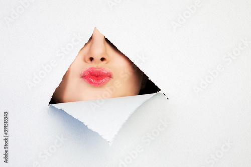 Girl sends aerial kiss through a hole in cardboard © Alla