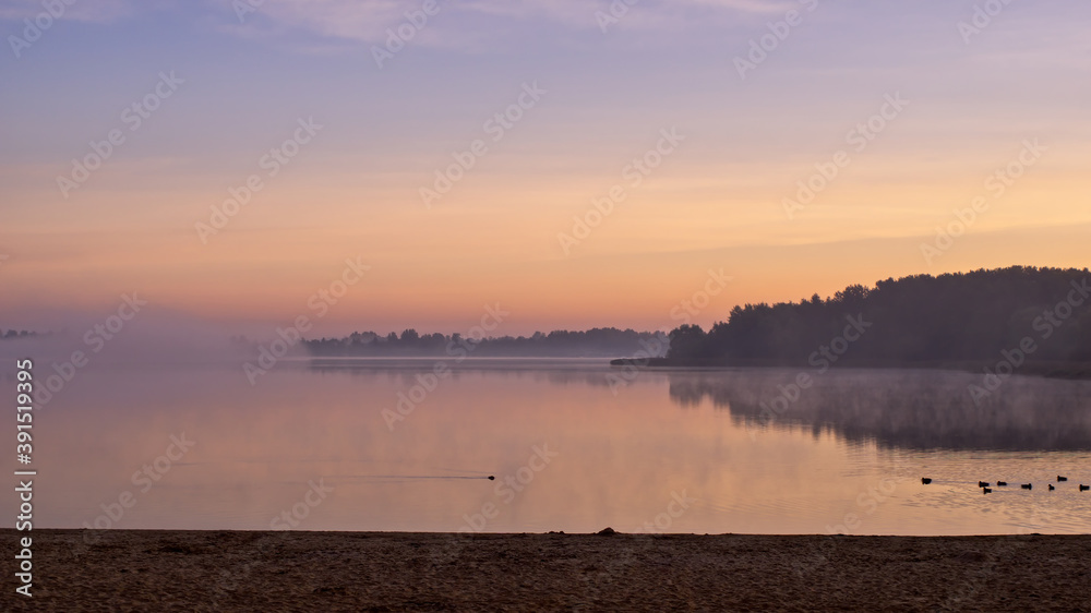 Horizontal landscape of a beach and a lake in sunrise.