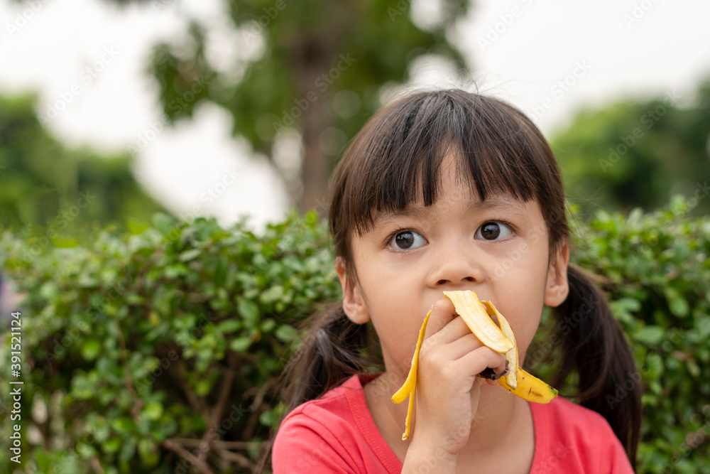 Little girl eating banana. The benefit of bananas is to help lower cholesterol levels. Little girl eating banana. The benefit of bananas is to help lower cholesterol levels.