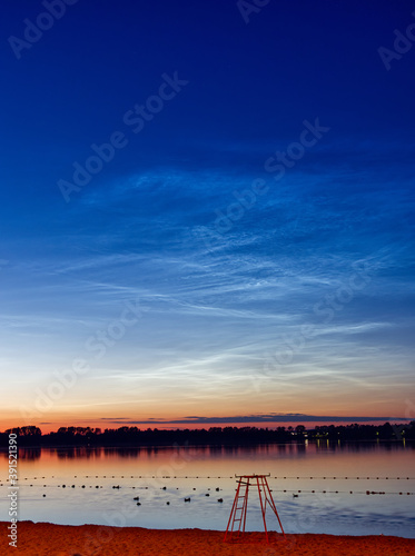 Noctilucent clouds also known as a night shining clouds over a lake.