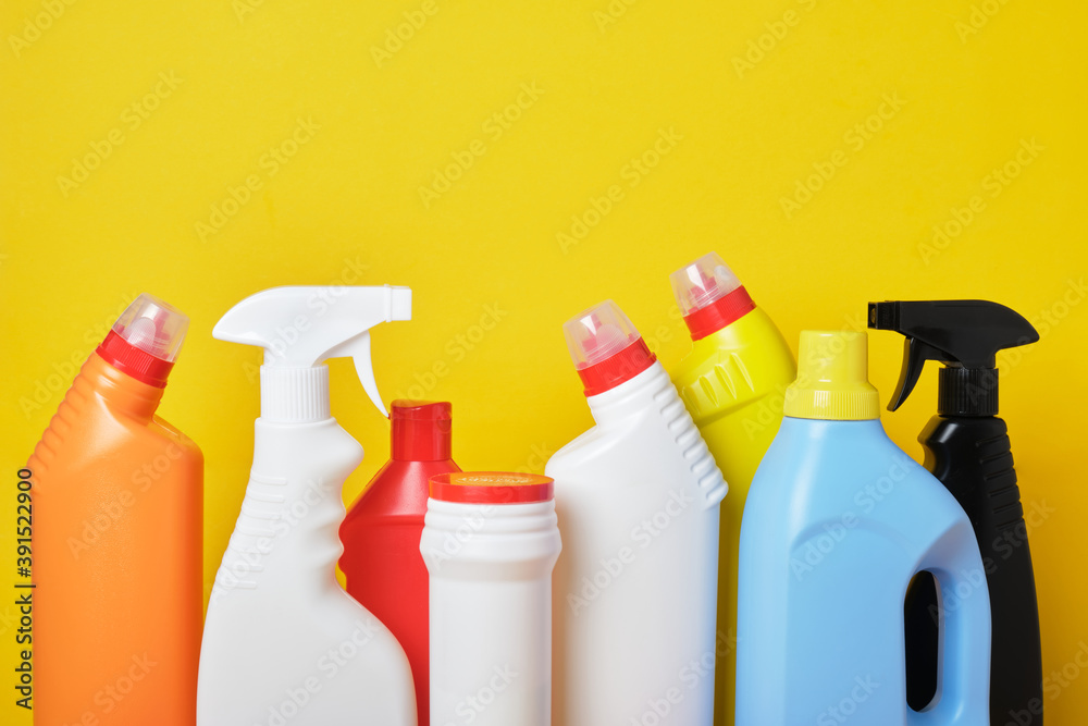 Colored plastic detergent bottles on yellow background Colored plastic detergent bottles on yellow background