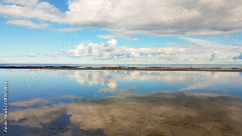 Calm sea on a sunny summer day. Blue cloudy sky reflection in tranquil water. Holiday and travel concept. Latvian nature.