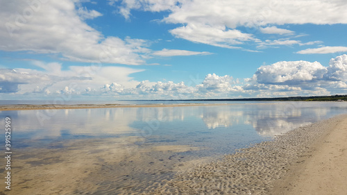 Calm sea on a sunny summer day. Blue cloudy sky reflection in tranquil water. Holiday and travel concept. Latvian nature.