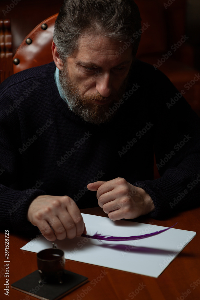 Writer with beard thinks over white sheet Writer with beard thinks over white sheet