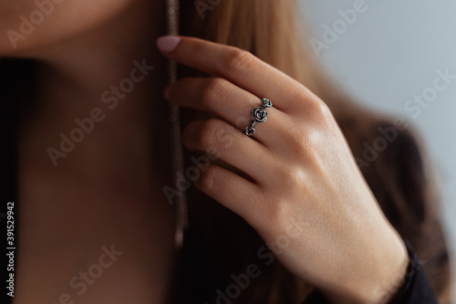 Silver rose ring on a middle finger of a young blonde lady. Close-up.