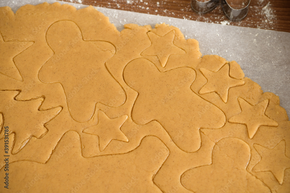 cut gingerbread out of the dough using a gingerbread mold, top view, raw dough with cinnamon prepared for baking . the pattern on the dough of the figures