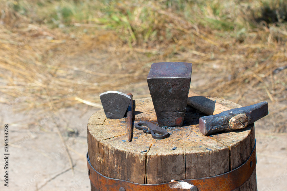 The old tools of a blacksmith on a large wooden stump The old tools of a blacksmith on a large wooden stump
